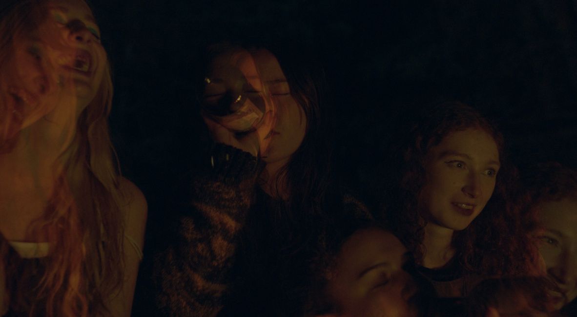 Emily and her fellow campers sitting around a campfire drinking