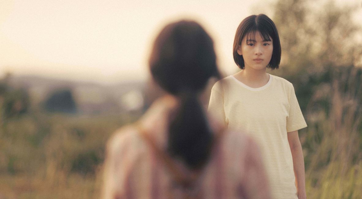 Kyomoto, with her back turned to camera, stares at Fujino